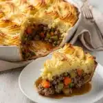 Golden crispy shepherd's pie with savory ground beef filling in ceramic dish.
