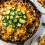 Skillet beef and rice taco casserole with melted cheese and browned beef.