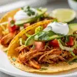 Slow cooker chicken tacos with creamy avocado and crispy toppings plated close up