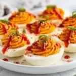 Spicy Sriracha deviled eggs with creamy filling and green onion garnish.