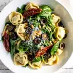 Creamy spinach tortellini pasta salad with sun-dried tomatoes and olives.