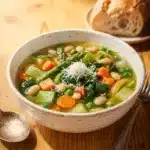 Spring Minestrone with vibrant peas and asparagus in a rustic white bowl.