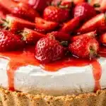 No-bake strawberry cheesecake pie slice with glossy berry topping on white plate.