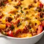 Stuffed pepper casserole with ground beef and melted cheddar cheese in a baking dish