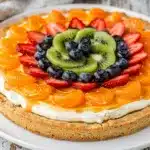 Sugar cookie fruit pizza with cream cheese frosting and fresh glazed fruit.