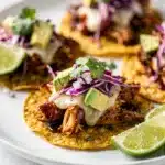 Crispy BBQ chicken tostadas with avocado and beans on a wooden table.