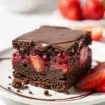 Chocolate covered strawberry brownies with distinct fudgy layers and glossy ganache