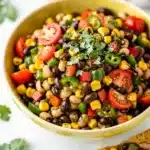Colorful cowboy caviar dip with chips in a rustic white bowl for serving.