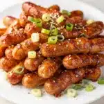 Firecracker hot dogs recipe with sticky glaze and green onion garnish.