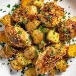 Golden crispy garlic parmesan chicken and potatoes on a rustic baking sheet.