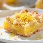 Lemon crumb bars feature a vibrant lemon curd layer and buttery shortbread crust.