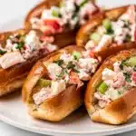 Mini lobster rolls with creamy salad on toasted buns in natural light