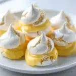 Crisp mini meringues filled with vibrant lemon curd on a slate board.