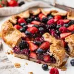 Mixed berry galette close up on rustic wooden board.