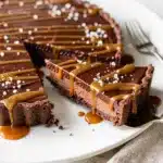 No bake chocolate tart with glossy filling and salted caramel drizzle on marble