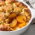 Golden peach cobbler with melting vanilla ice cream closeup