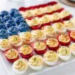 Patriotic deviled eggs with red white and blue creamy filling for July Fourth