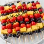 Patriotic fruit kabobs with watermelon pineapple strawberries and blueberries.