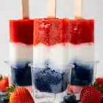 Patriotic popsicles with strawberry coconut and blueberry layers on marble