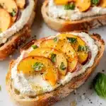 Peach bruschetta with whipped ricotta on toasted bread, honey, and basil.