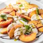 Juicy peach caprese salad with mozzarella, basil, olive oil, and balsamic glaze.