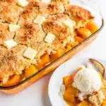 Golden brown peach cobbler with melting vanilla ice cream