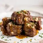 Slow cooker garlic butter beef bites in a glossy sauce with rustic plating.