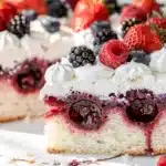 Moist white poke cake soaked with vibrant berry syrup and fresh berries